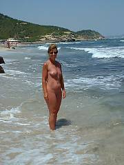 Hard body grandma out on vacation, getting naked on the warm beach and giving a hand job